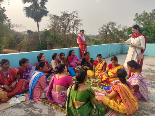 Women artisans in a rural setting attentively participating in a hands-on workshop, learning the intricate techniques of crafting Dhokra jewelry.